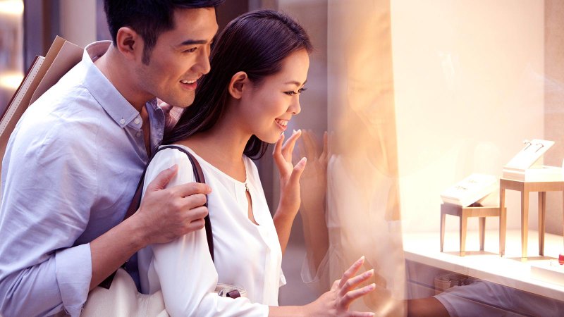 a couple looks at jewelry in a shop window