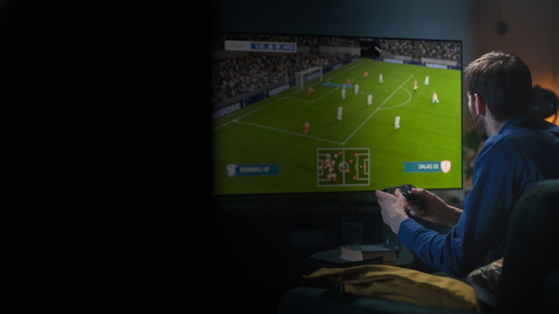 Person playing a football video game on a TV screen at home