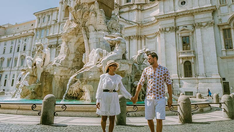 People holding hands, with a fountain in the background