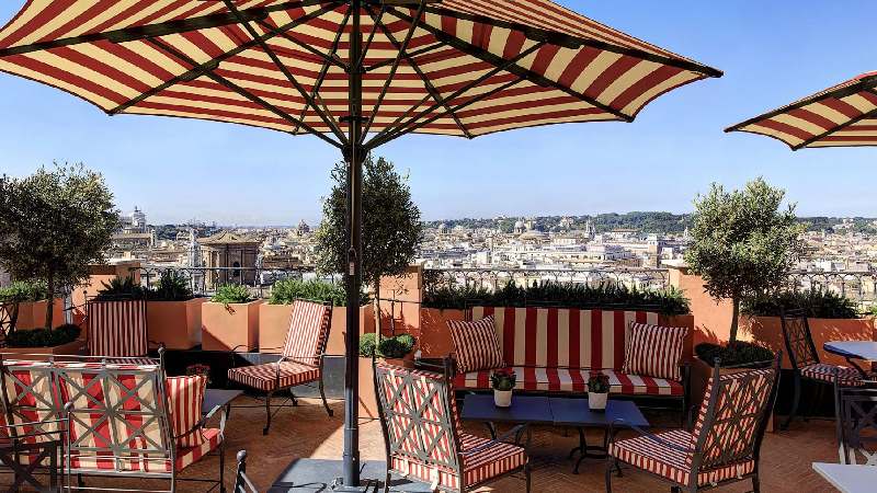 Rooftop terrace with striped seating, large umbrellas, and panoramic city views