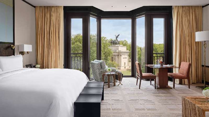 Spacious hotel room with floor-to-ceiling windows overlooking a monument and park
