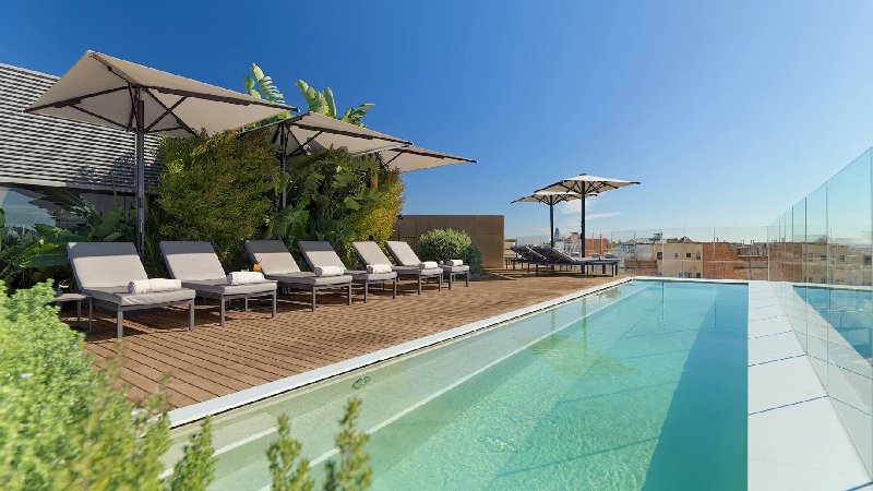 Rooftop swimming pool with sun loungers, umbrellas, and clear city views