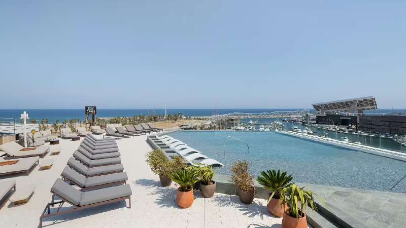 Rooftop infinity pool with sun loungers and views of the sea and marina