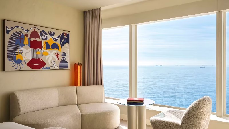 Bright hotel room seating area with modern artwork and panoramic ocean view