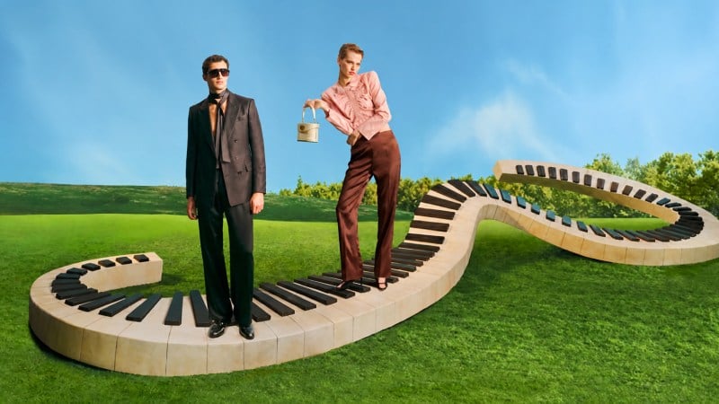 Fashion models posing on a winding piano walkway in a green field under a blue sky